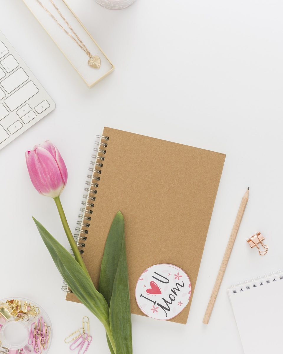 Kraft notebook with a pink tulip and a small candle on a white table