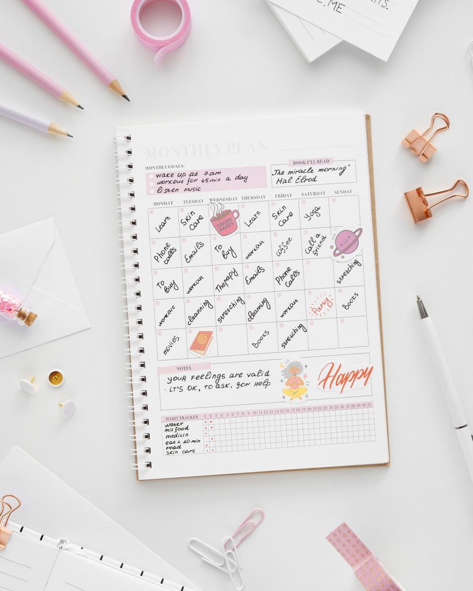 Open bullet journal with a pastel weekly spread, washi tape and markers on a white desk