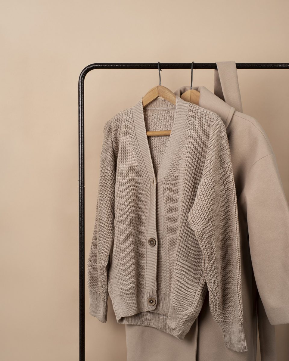 Beige knit cardigan on a hanger on a minimal clothing rail