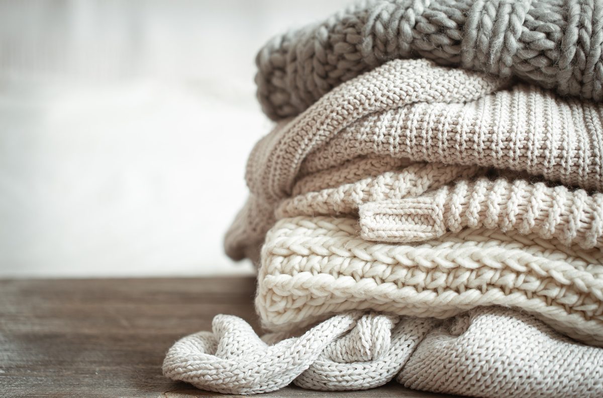 Stack of neatly folded cream knit sweaters