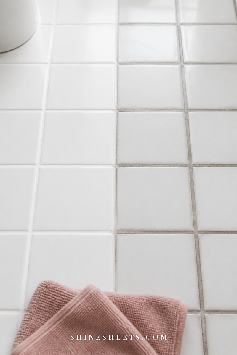 Close-up of white square bathroom tiles with half the grout lines bright and clean and half grayed, soft daylight