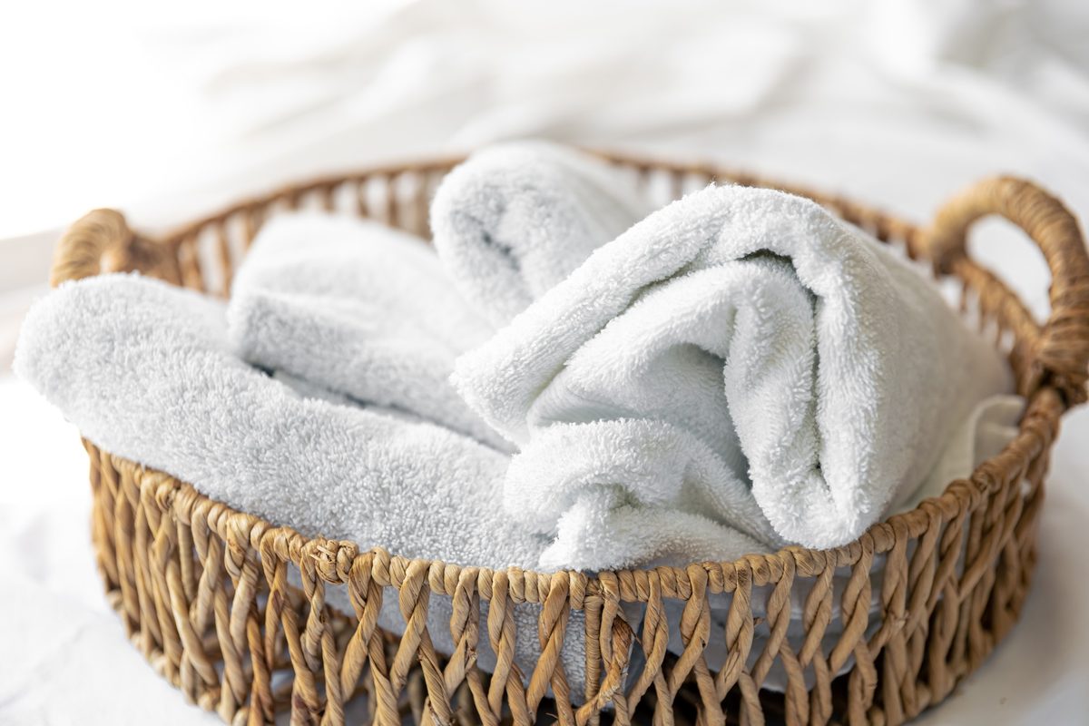 Soft white towels in a woven basket in bright light