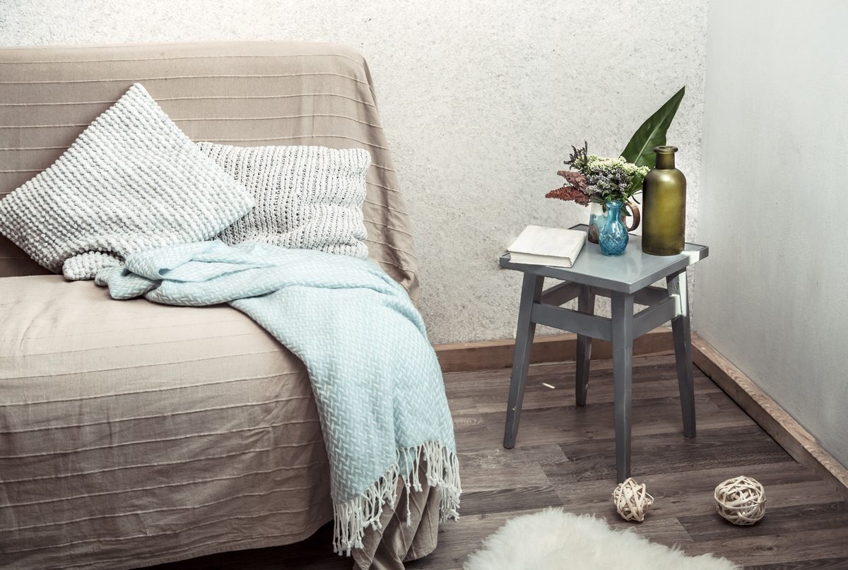 Beige sofa with a mint knit throw and a small side table in a calm living room