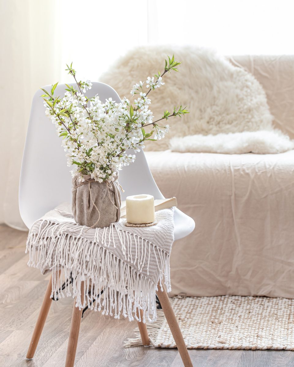 Cozy corner with a white side table, a vase of blossoms and a soft armchair