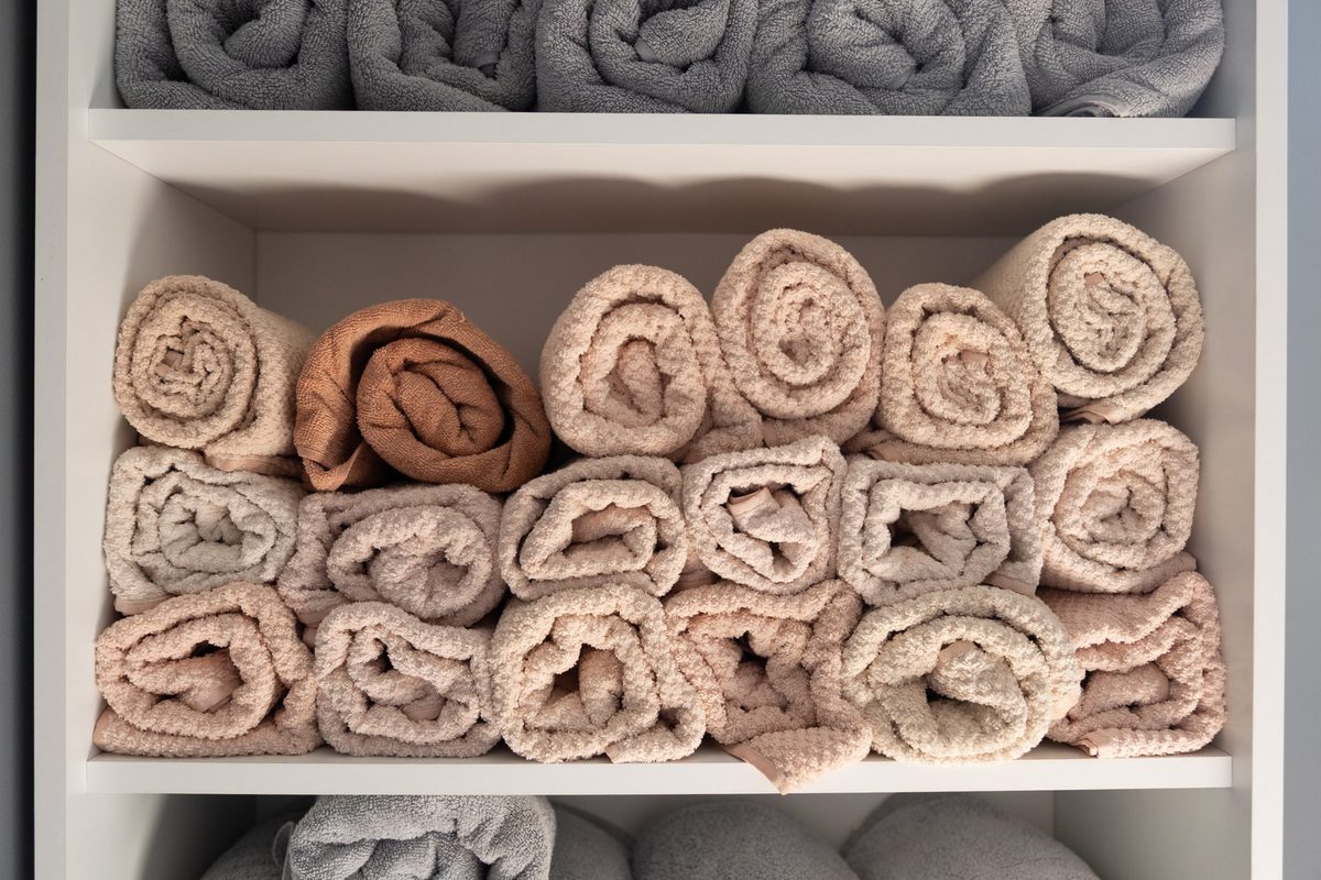 Rolled towels in soft neutrals on white open shelves