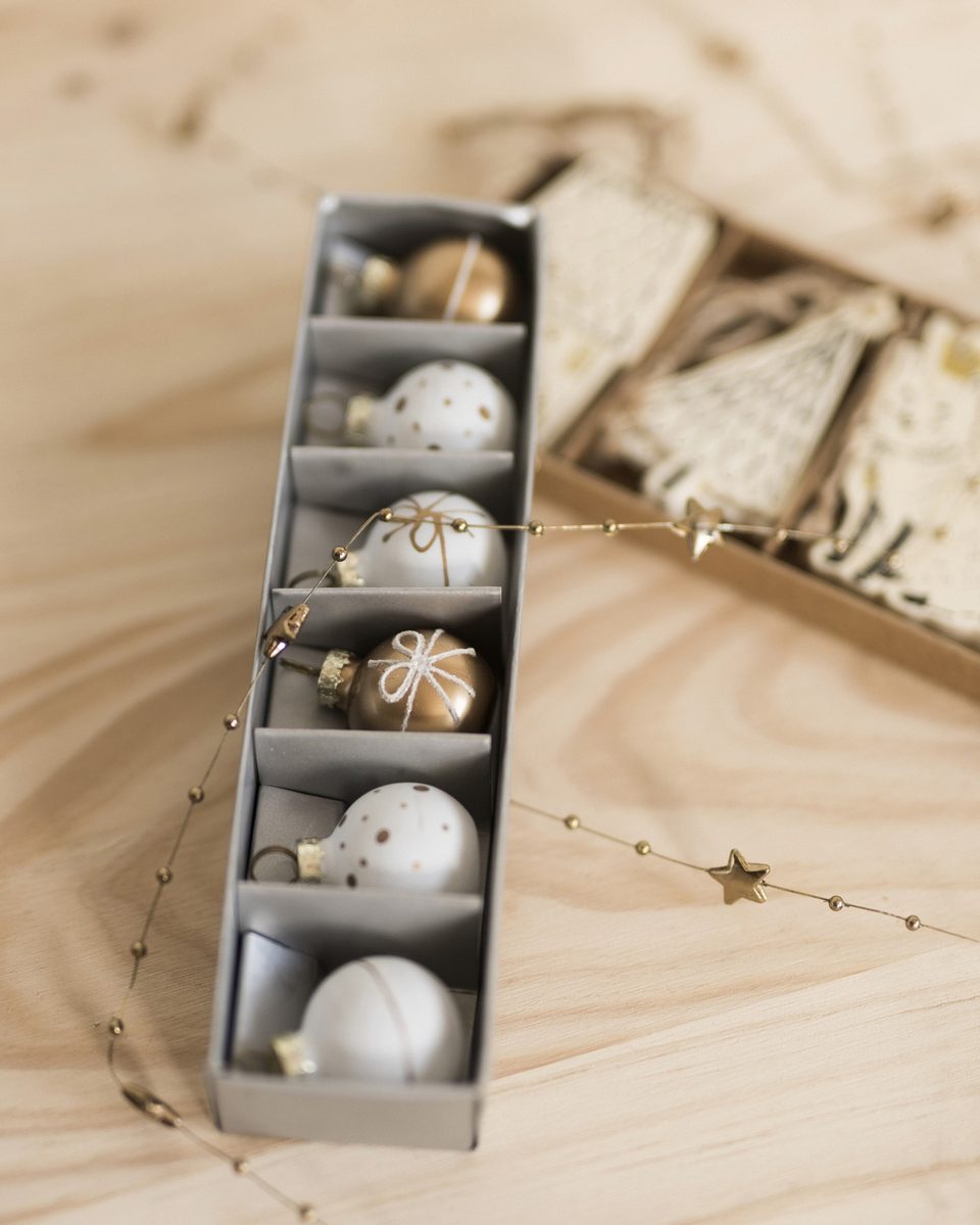 Silver ornaments stored in a cardboard tray beside wrapped decorations