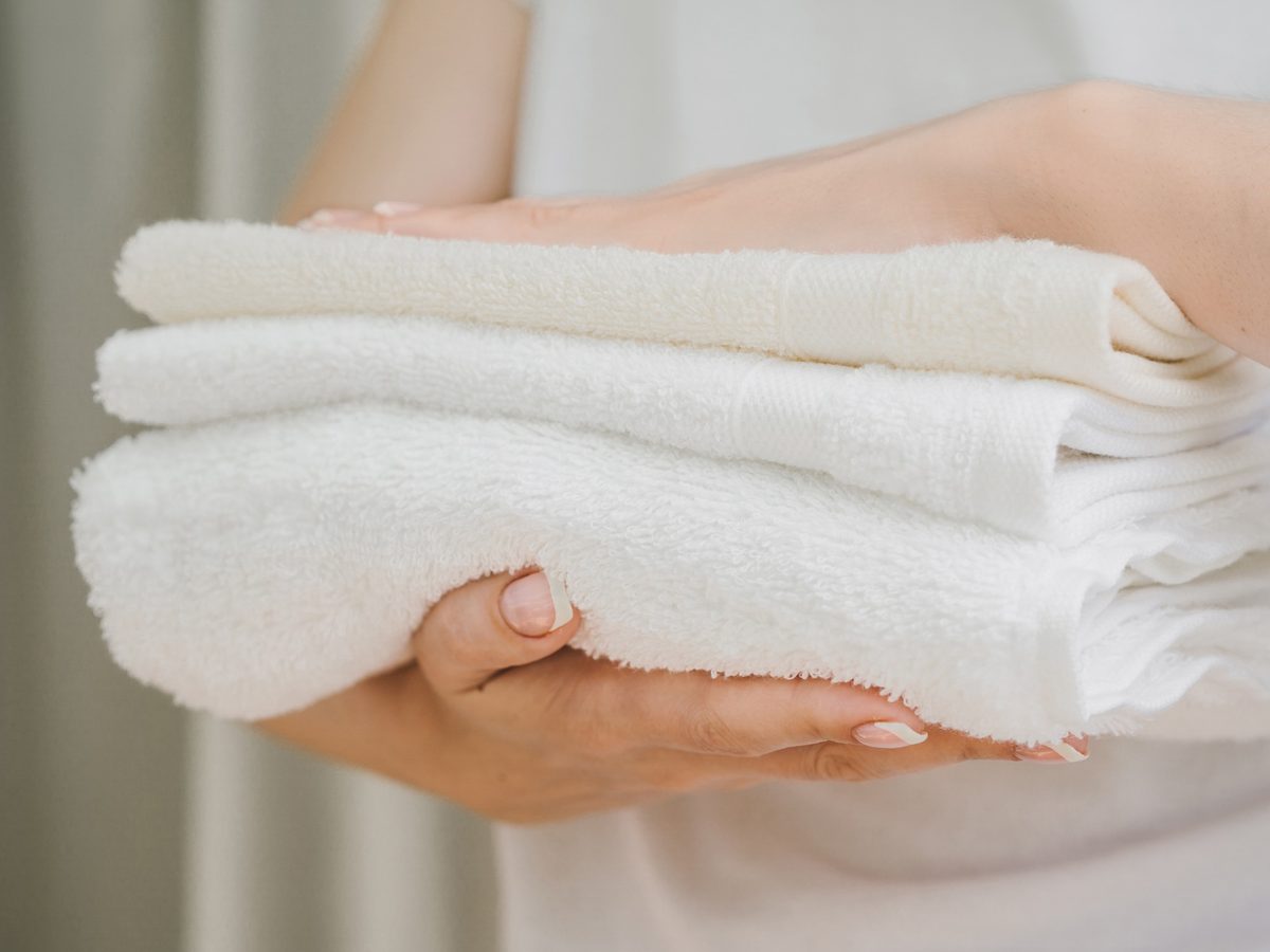 Woman's hands holding a stack of clean folded white towels