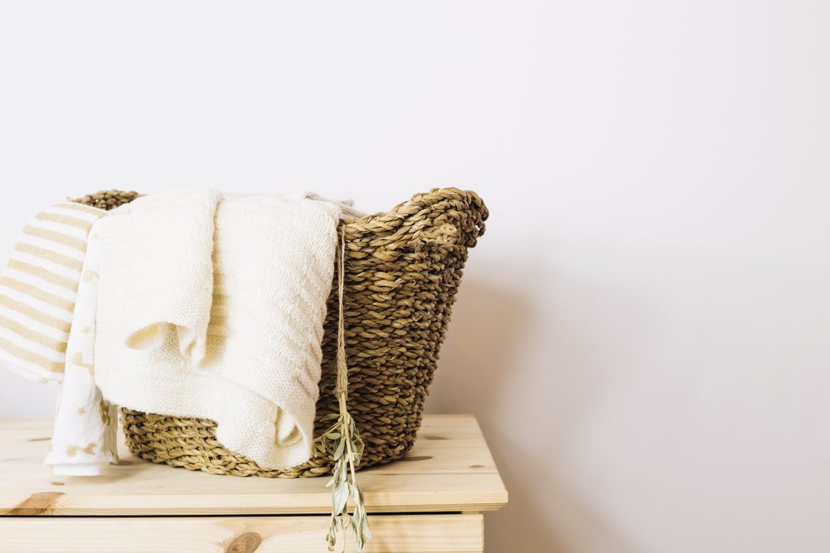 Cream blanket draped over a woven basket on a wooden dresser