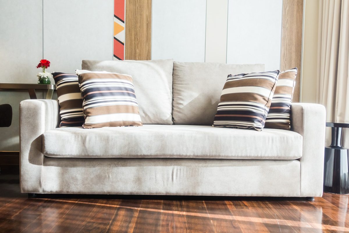 Cream sofa with striped, floral and textured cushions in blush and beige tones in a bright living room