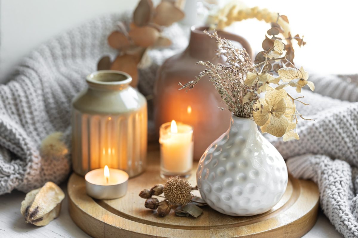 Brass candle holders with ivory taper candles and a white ceramic vase on a light wood coffee table