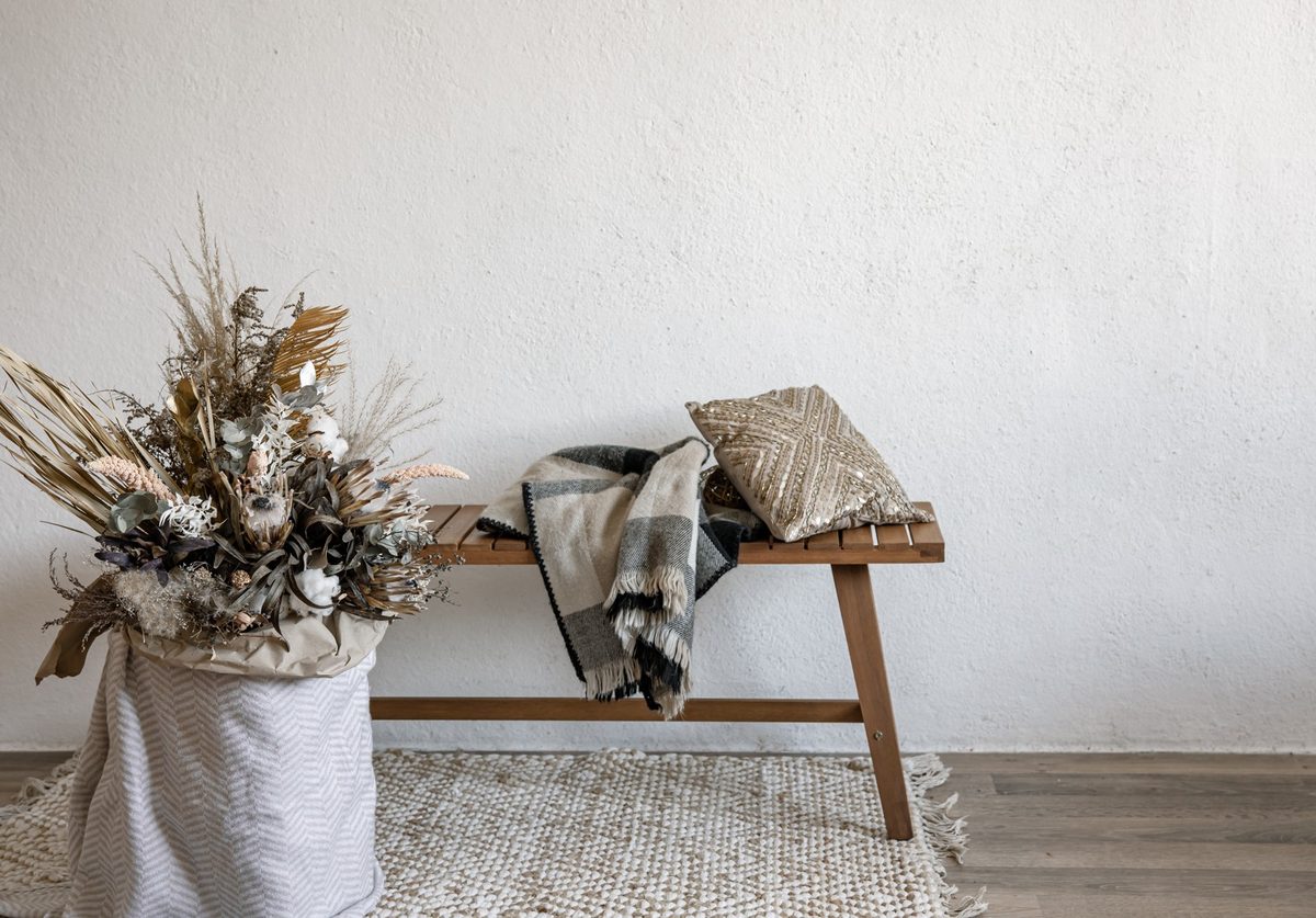 Neutral living room with a cream boucle sofa, beige linen curtains, a jute rug and a white ceramic vase with dried branches