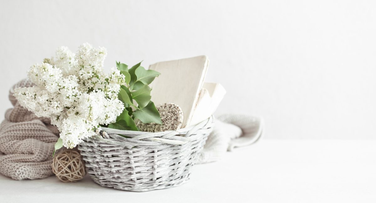 White wicker basket with lilac flowers and a knit blanket