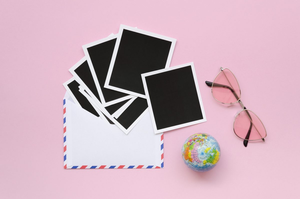Instant photos, an envelope and pink sunglasses on a pink background