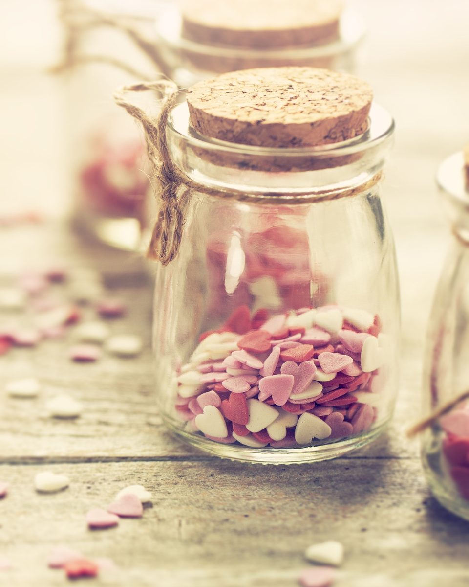 Small glass jar filled with paper hearts and petals