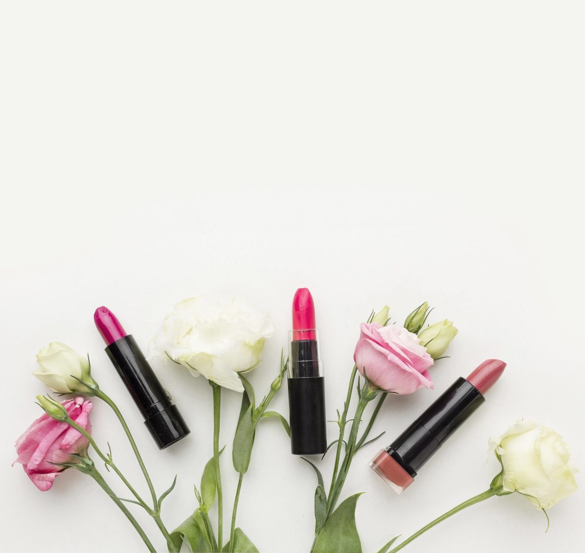 Pink and red lipsticks with white roses on a white background