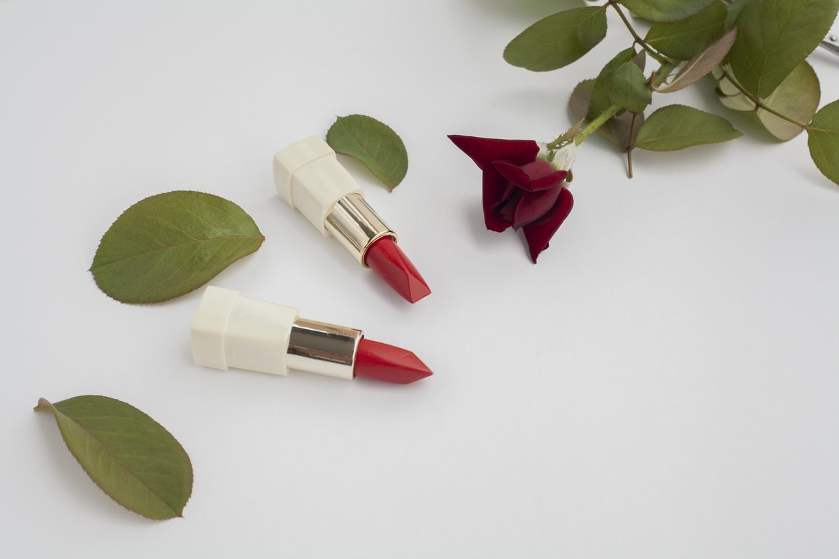 Red lipsticks and a red rose on a white background